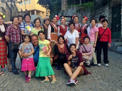 A group of tourists posing with women in traditional Bulgarian clothes