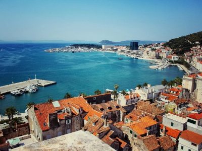 Coastal view of Split, Croatia, with red-tiled rooftops and a vibrant harbor meeting the Adriatic Sea.