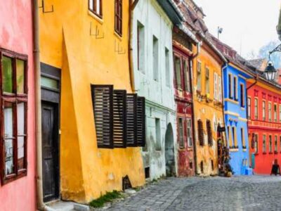 Bright, narrow cobbled street in Sighisoara, Romania, with colorful houses from medieval times.