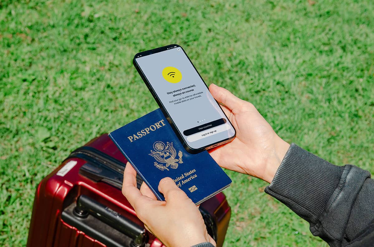 A person holding a US passport and a phone installing an e-SIM plan
