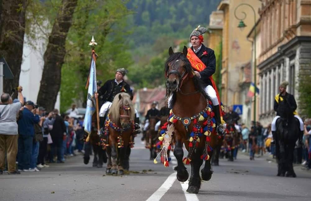 Men on horseback trot through Brasov, Romania during Junii Brașovului Parade