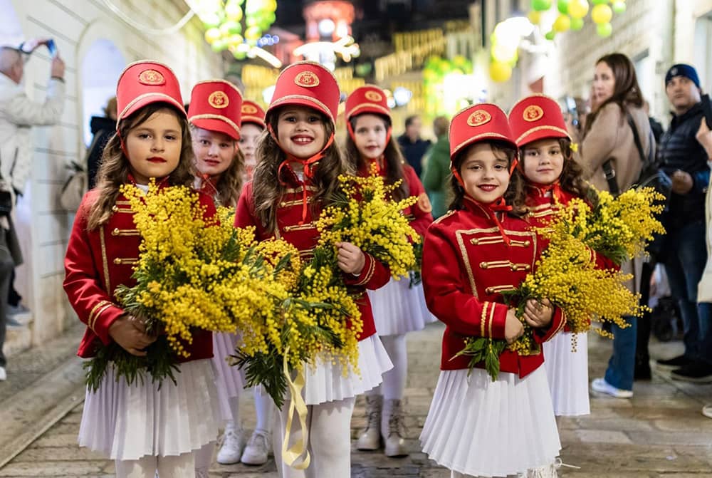 Children holding mimosa flowers celebrating the Mimosa Festival, Montenegro